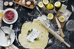 Pâte étalée sur un plan de travail noir avec rouleau et citrons