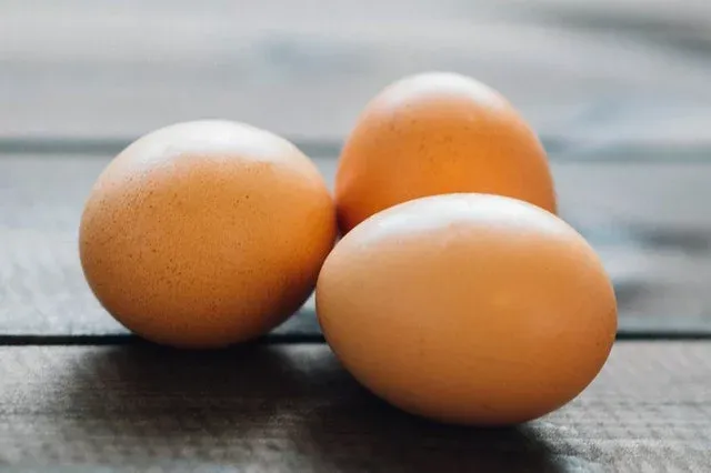 Trzy brązowe jajka na drewnianym blacie