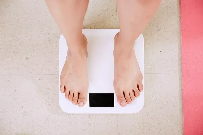 Pieds nus d'une personne sur un pèse-personne blanc