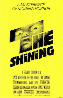 The Shining film poster, a face staring out from behind the title on yellow